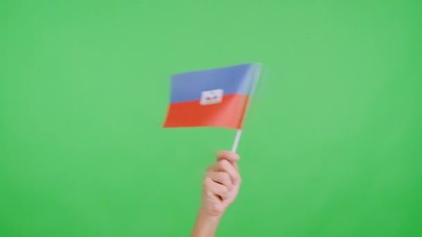 スタジオでのスローモーションビデオ ハイチの国旗のペナントを横から横に振る手のクロマ — ストック動画