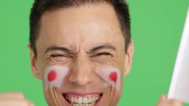 影片在演播室里的彩色特写是一名男子的近照 他的脸上挂着一面日本国旗 以支持日本队 — 图库视频影像