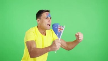 Stüdyoda, Avustralya ulusal bayrağını sallayan, hakemlerin kararına kızgın bir adamın krom görüntüsü var.