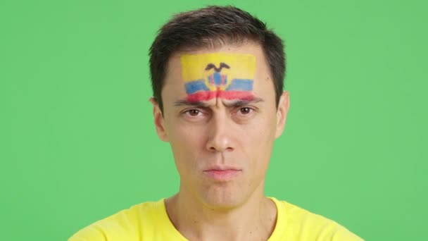 カメラを見ている顔にエクアドルの旗が描かれた深刻な男のクロマのスタジオでのビデオ — ストック動画