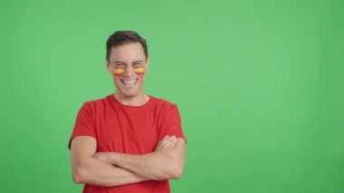 Stüdyoda, kollarını kavuşturup gülümseyen İspanyol bayrağıyla kameraya bakan bir adamın kromasıyla.