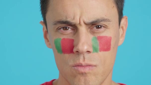摄影棚里的录像 彩色的是一个严肃男子的特写 他的脸上挂着葡萄牙国旗 看着镜头 — 图库视频影像