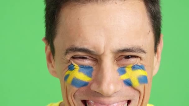 摄影棚里的录像 彩色的是一个白人男子的特写 脸上挂着瑞典国旗 在镜头前微笑 — 图库视频影像