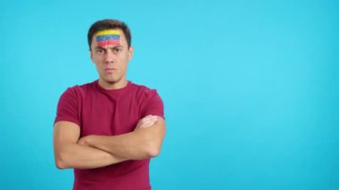 Stüdyoda, Venezuela bayraklı, ağırbaşlı ve ciddi bir adamın rengiyle çekilmiş bir video var. Kameraya haysiyetle bakıyor.