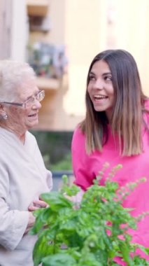 Yaşlı bir kadınla yaşlı bir kadının terasta şarkı söylediğini gösteren bir video.
