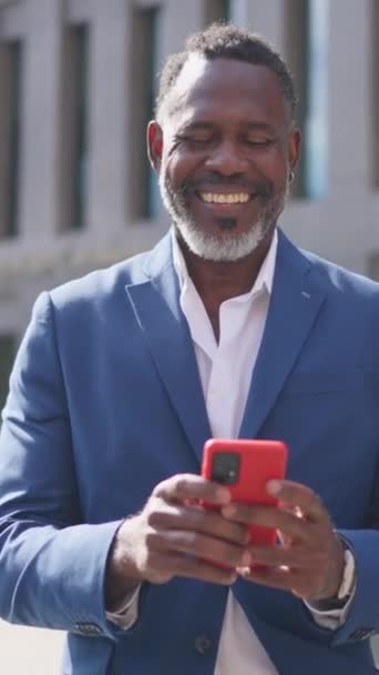 视频与放大一个快乐的非洲商人使用手机在金融大楼外 — 图库视频影像