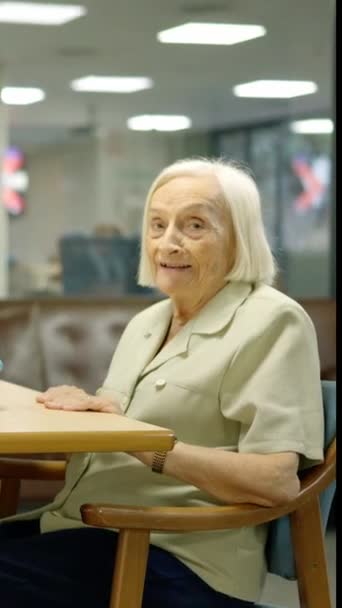 Видео Пожилой Женщины Смотрящей Камеру Сидящей Рядом Столом Играми Доме — стоковое видео