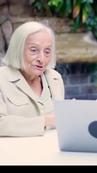 Video Mormor Vinka Ett Videosamtal Med Bärbar Dator Sitter Trädgård — Stockvideo