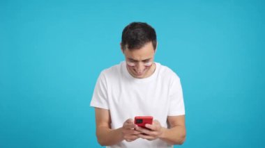 Polonyalı bir destekçinin krom arkaplanlı stüdyo videosu yüzünde Polonya bayrağı ile cep telefonuna bakıp gülümsüyor ve onu krom tuşlu ekranla kameraya gösteriyor.