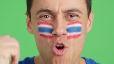 Stüdyoda, yüzünde Tayland bayrağı olan ve Tayland takımını destekleyen bir adamın krom görüntüsü var.