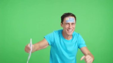 Stüdyoda Uruguay 'ı coşkuyla alkışlayan ve ulusal bayrak sallayan bir adamın renkli videosu var.