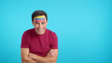 Stüdyoda, yüzü Venezuela bayrağıyla boyanmış kolları bağlı gülümseyen bir adamın kromasıyla.