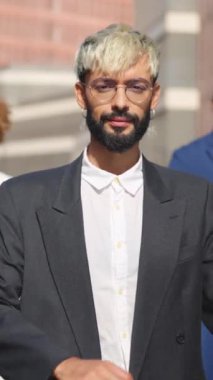 Açık havada iş arkadaşlarının yanında kollarını kavuşturan gülümseyen genç iş adamının videosu.