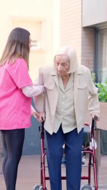 护理人员的录像帮助一位老年妇女在户外站起来 — 图库视频影像