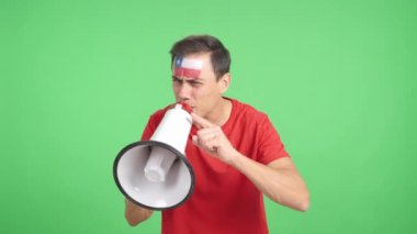 Stüdyoda, yüzünde Şili bayrağı olan bir adamın krom görüntüsüyle kalabalığı megafonla topluyor.