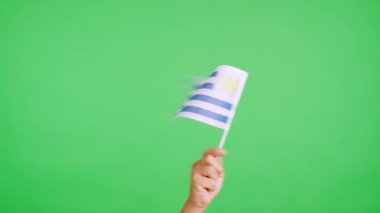 Stüdyoda Uruguay bayrağının bayrağını sağa sola sallayan bir elin kromasıyla yavaş çekim videosu