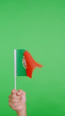 Stüdyoda yavaş çekim videosu. Rüzgâr tarafından el sallanırken Portekiz flamasını kaldıran bir elin krom rengi.