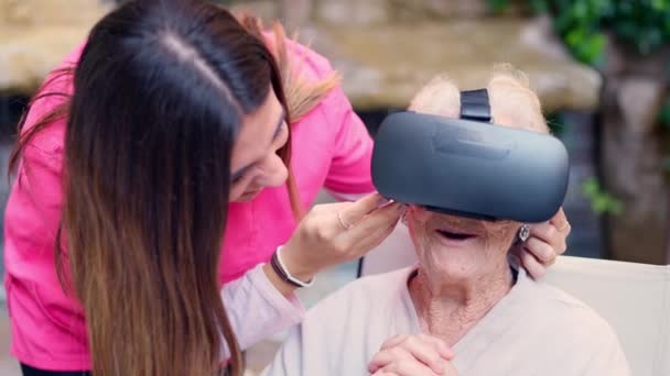 Wideo Zdumioną Starszą Kobietą Okularach Wirtualnej Rzeczywistości Obok Pielęgniarki — Wideo stockowe