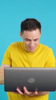 Stüdyoda, mutlu bir adamın dizüstü bilgisayar kullanıp gülümseyen mavi arkaplanlı videosu. Çerçeve boş başlar, adam aşağıdan görünür ve altta kaybolur..