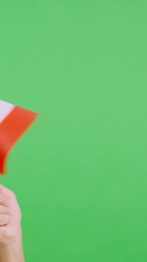 Stüdyoda, bir elin krom renginde, Kanada bayrağının bayrağını sağa sola salladığı yavaş çekim videosu.