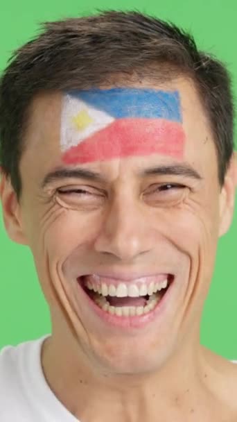 摄影棚里的录像 彩色的是一个男人的特写 他脸上挂着菲律宾国旗 在镜头前微笑 — 图库视频影像