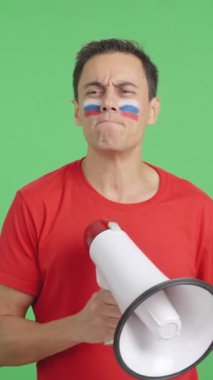 Stüdyoda, yüzünde Rus bayrağı olan bir adamın krom rengiyle kalabalığı megafonla topladığı bir video.