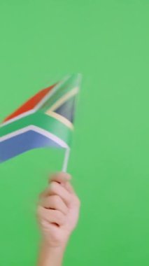 Stüdyoda, Güney Afrika bayrağının bayrağını sağa sola sallayan bir elin kromasıyla yavaş çekim videosu.