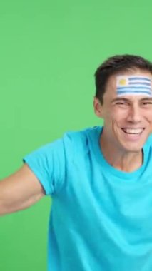 Stüdyoda Uruguay 'ı coşkuyla alkışlayan ve ulusal bayrak sallayan bir adamın renkli videosu var.