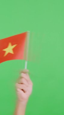 Stüdyoda, Vietnam bayrağının bayrağını sağa sola sallayan bir elin kromasıyla yavaş çekim videosu.