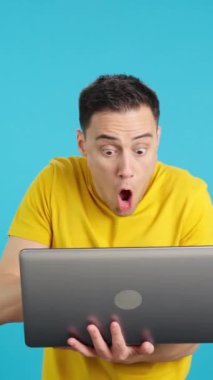 Stüdyoda, dizüstü bilgisayar kullanırken elini kaldıran bir adamın mavi arkaplanlı videosu. Çerçeve boş başlar, adam aşağıdan görünür ve altta kaybolur..