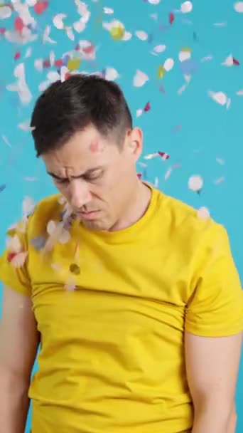 ビデオでスタジオで青の背景にA悲しいと動揺男取得Confettiスロー彼に — ストック動画