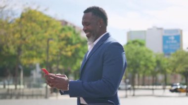 Sokakta telefonu kullanan gülümseyen Afrikalı iş adamının videosu.