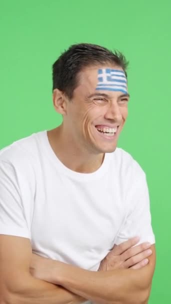 空白のコピースペースに顔を向けて描かれたギリシャの旗を持つ幸せな男のクロマとスタジオでのビデオ — ストック動画