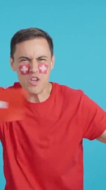 Stüdyoda İsviçre için coşkuyla tezahürat eden ve ulusal bayrak sallayan bir adamın renkli videosu var.