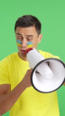 Stüdyoda, yüzünde Ukrayna bayrağı olan bir adamın krom rengiyle kalabalığı megafonla topladığı bir video.