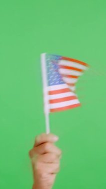 Stüdyoda, ABD bayrağının bayrağını sağa sola sallayan bir elin kromasıyla yavaş çekim videosu.