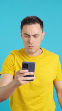 Stüdyoda cep telefonuna bakarken elini kaldıran bir adamın mavi arkaplanlı videosu. Çerçeve boş başlar, adam aşağıdan görünür ve altta kaybolur..