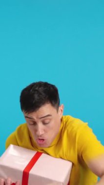 Stüdyoda, ağırlığı çok ağır bir hediye getiren bir adamın mavi arka planlı videosu var. Çerçeve boş başlar, adam aşağıdan görünür ve altta kaybolur..