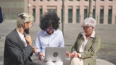 Haberleri kutlamak için dışarıda dizüstü bilgisayar kullanan iş adamlarının el kaldırdığı bir video.