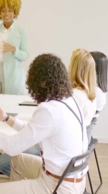 Toplantı odasındaki sunumdan sonra Afrikalı bir kadını alkışlayan iş arkadaşlarının yavaş çekim videosu.