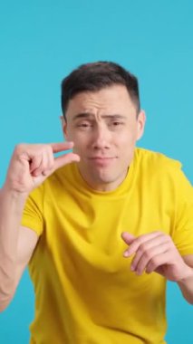 Stüdyoda mavi arka planı olan bir adamın parmaklarıyla küçük bir miktar gematize ettiği bir video.