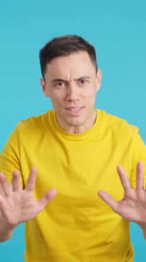 Stüdyoda mavi arka planda bir adam videosu var. Ellerle sakin olmanızı tavsiye ediyor. Çünkü her şey kontrol altında..