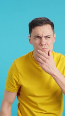 Stüdyoda ciddi bir adamın mavi arkaplanlı videosu kameraya bakıyor.