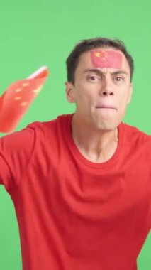 Stüdyoda, hakemlerin kararına kızgın bir şekilde elinde Çin bayrağı sallayan bir adamın kromasıyla.