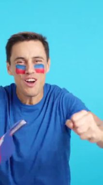 Stüdyoda Haiti için coşkuyla tezahürat eden ve ulusal bayrak sallayan bir adamın krom görüntüsü var.