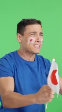 Stüdyoda, elinde japon bayrağı sallayan, hakemlerin kararına kızgın bir adamın krom görüntüsü var.