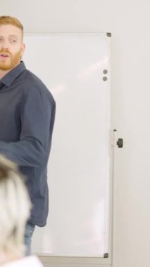 Toplantıda açıklama yaparken beyaz tahta kullanan bir adamın yavaş çekim videosu.