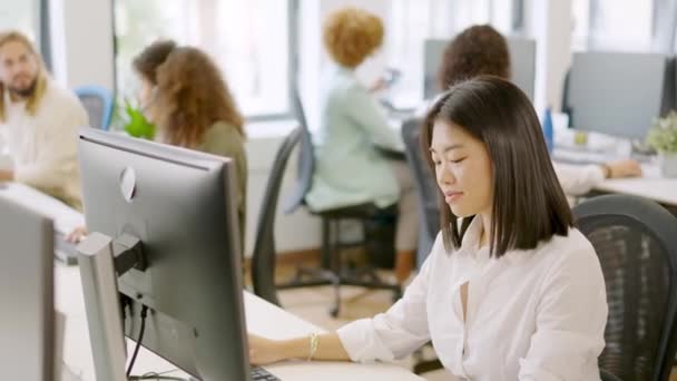 一个亚洲女人和其他同事在一个愉快的工作环境中工作的慢动作视频 — 图库视频影像
