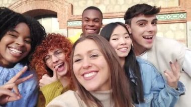 Bir grup gülen çoklu etnik arkadaşın şehirde selfie çekerken el kol hareketi yaptığı bir video.