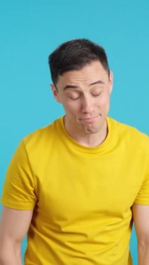 Stüdyoda mavi arka planı olan bir adam kredi kartını gösteriyor ve kameraya gülümsüyor.